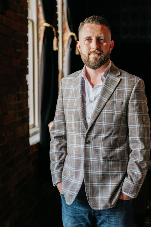 A man in a suit standing next to a brick wall.